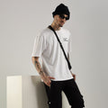 A male model wearing black ultra joggers with a drawstring waist, deep side pockets, and ribbed cuffs, paired with a white t-shirt and a beanie.