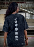 Person wearing a black t-shirt with moon phase design in an urban setting