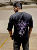 Person wearing a black t-shirt with a purple design on the back in an indoor setting.