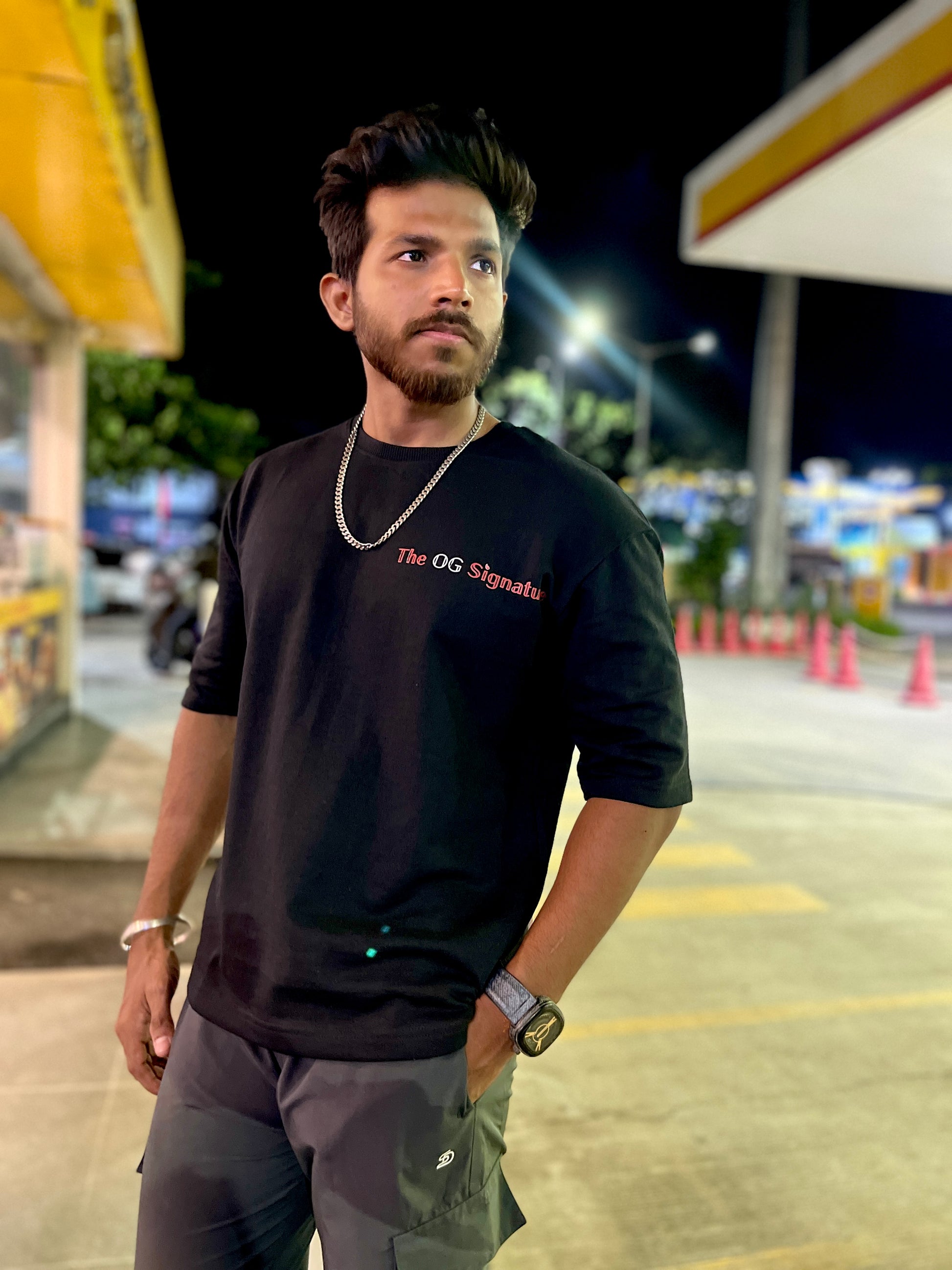 Man wearing a black t-shirt with text in a parking lot at night