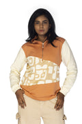 Woman wearing a patterned orange and beige top with a white background