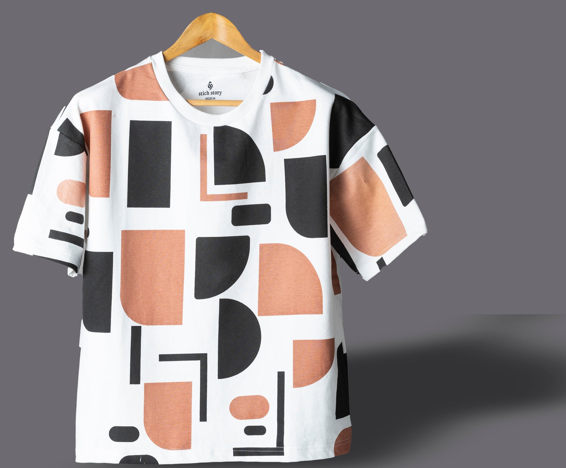 White t-shirt with geometric pattern on a hanger against a gray background