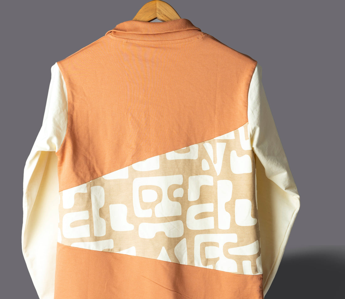 Orange and white pullover with geometric pattern on a gray background