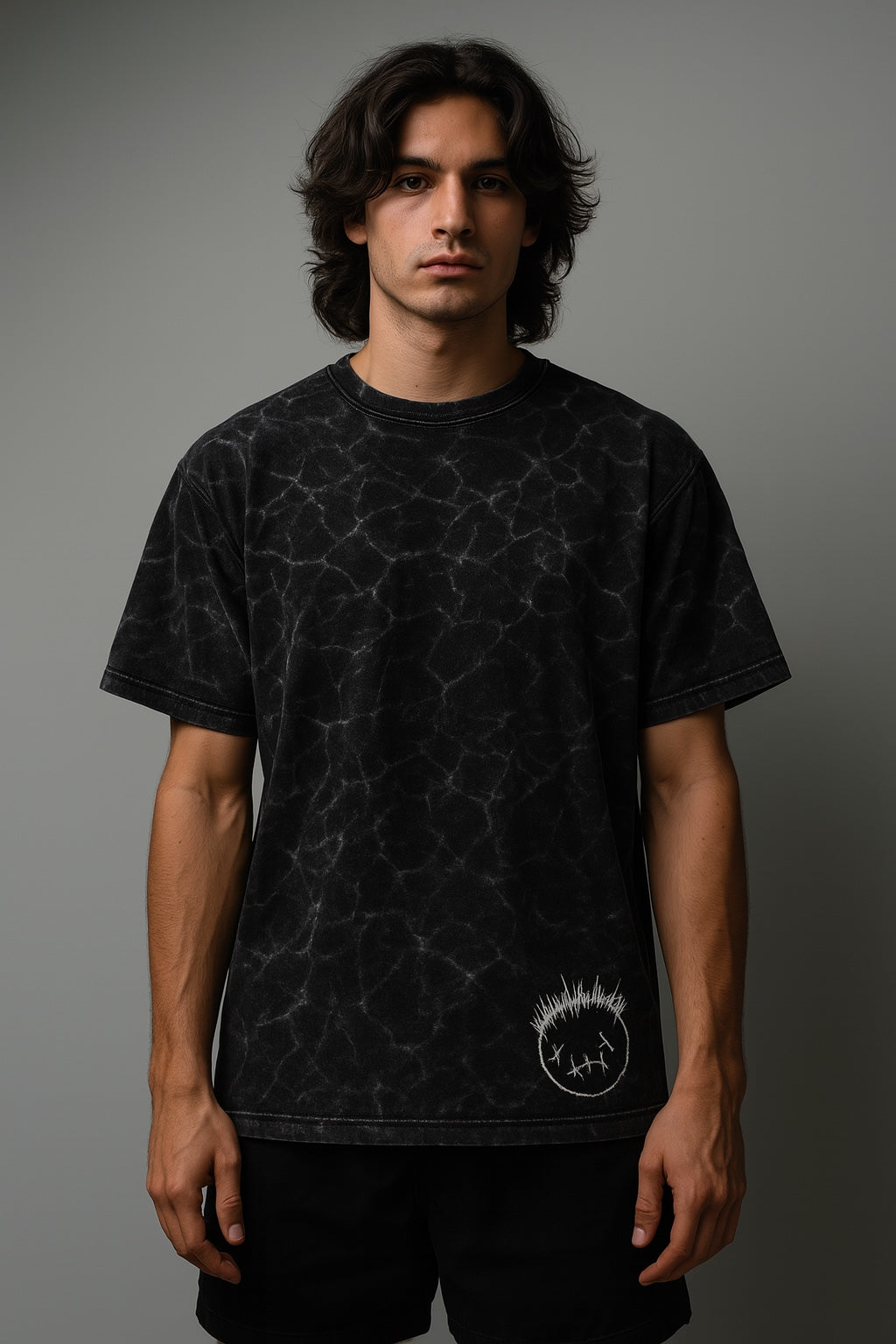 Person wearing a black t-shirt with a geometric pattern and logo on a gray background