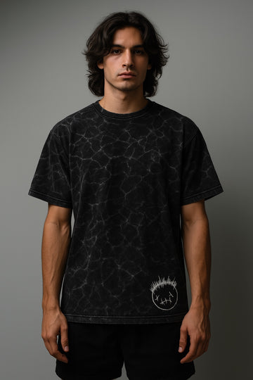 Person wearing a black t-shirt with a geometric pattern and logo on a gray background