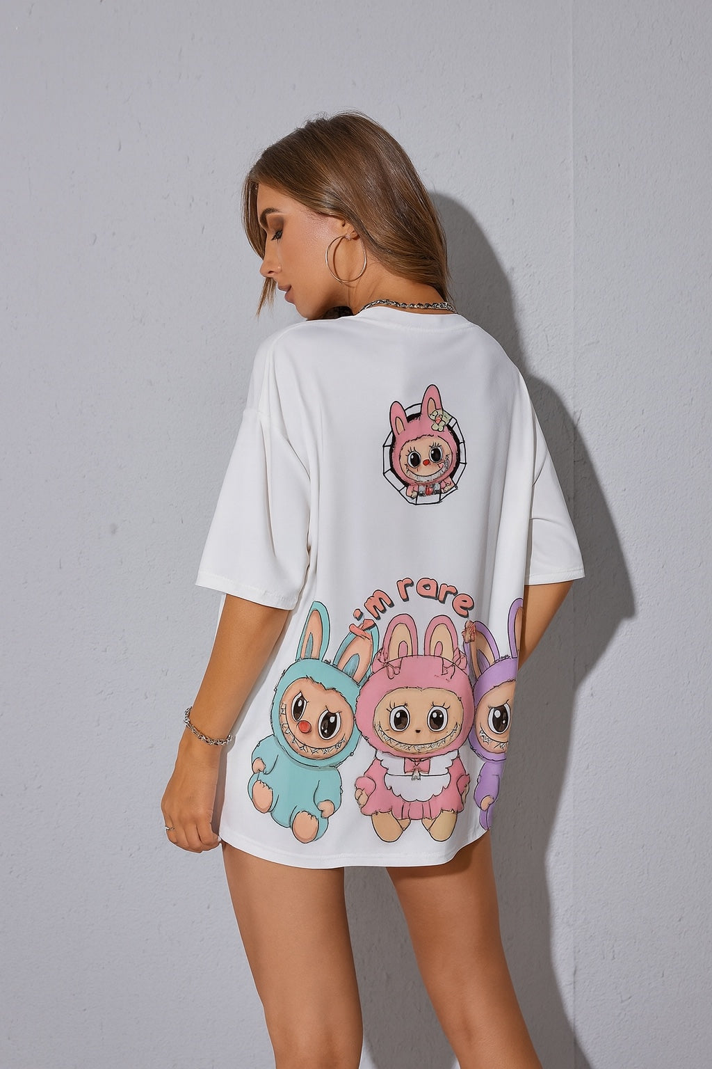 Person wearing a white t-shirt with cartoon character designs on the back against a plain background