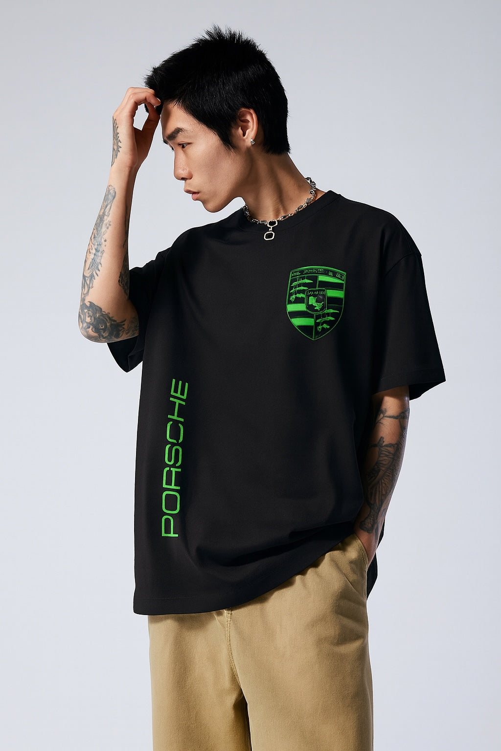 Person wearing a black Porsche t-shirt with green logo and text on a plain background