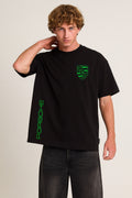 Person wearing a black t-shirt with green Porsche logo on a beige background