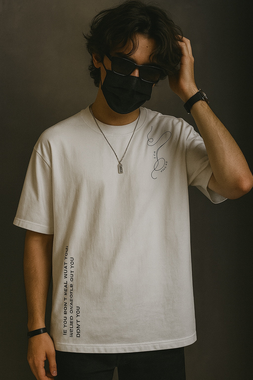 Person wearing a white t-shirt with text and a black mask against a dark background