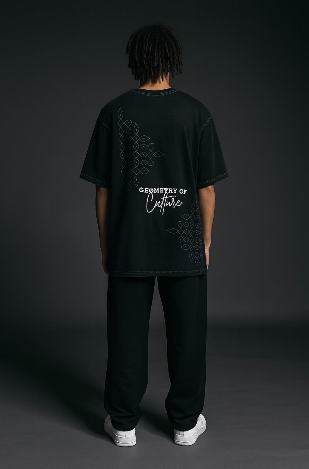 Person wearing a black t-shirt with white text on the back against a dark background