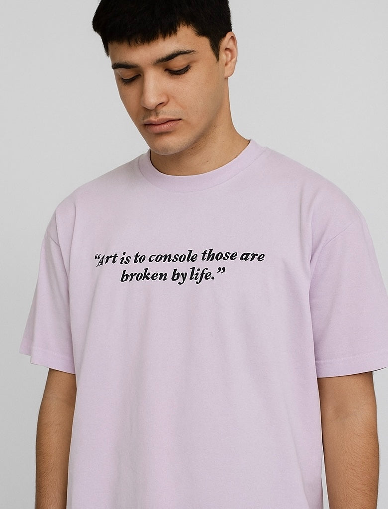 Person wearing a light purple t-shirt with a quote on a plain background