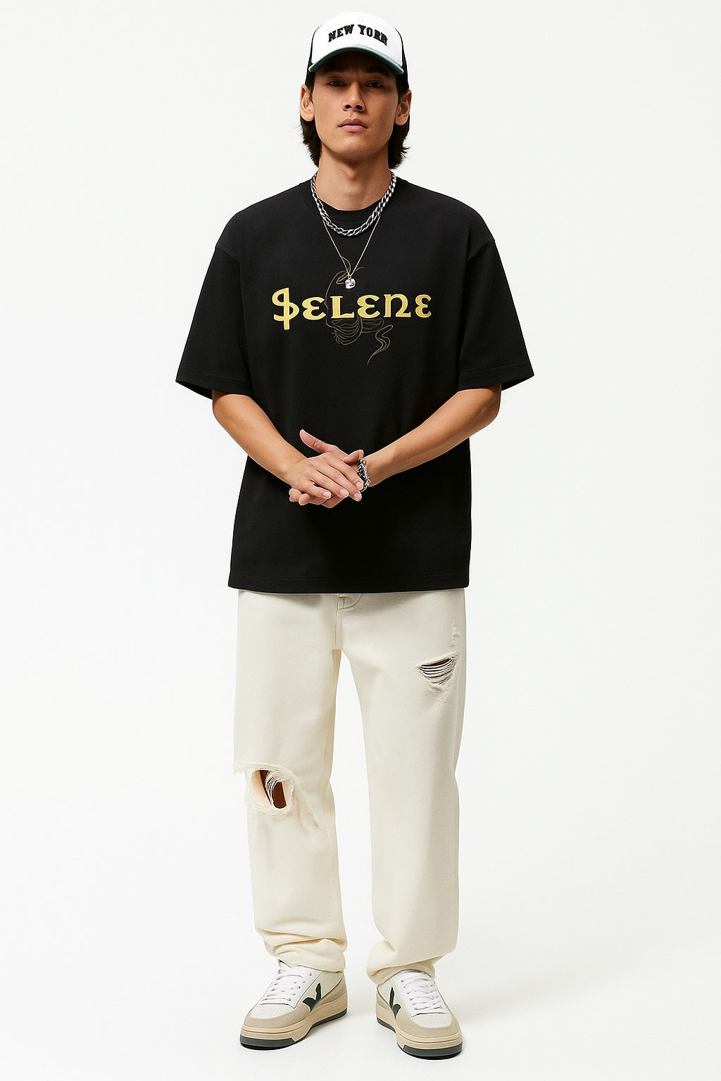 Person wearing a black t-shirt with 'Selene' text, white pants, and a cap on a white background